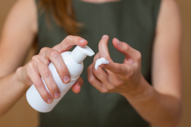 Mujer rubia aplicando una crema en la mano