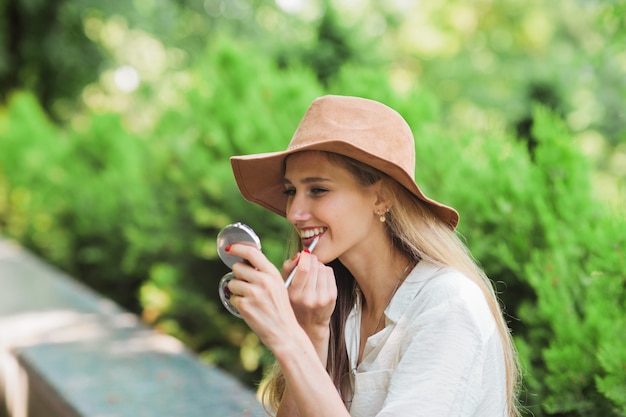 Mujer rubia aplicando lápiz labial en los labios