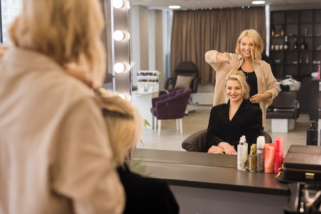 Foto mujer rubia arreglándose el pelo