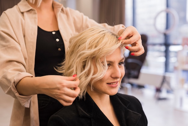 Foto mujer rubia arreglándose el pelo