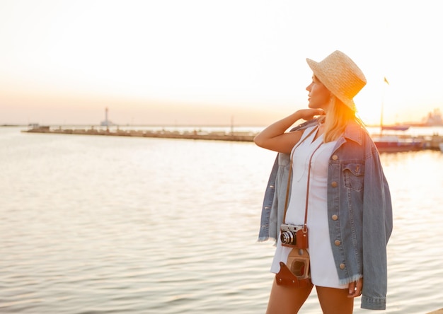 Mujer rubia atractiva alegre y alegre al amanecer en la playa. Concepto de viaje y ocio.