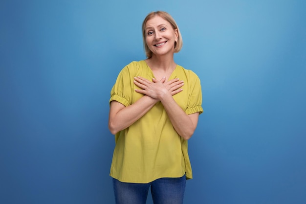 Mujer rubia atractiva en camiseta amarilla sobre fondo azul