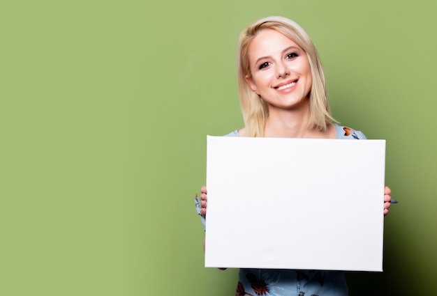 Mujer rubia con bandera blanca en la pared verde