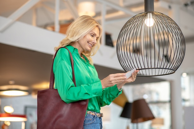 Mujer rubia en una blusa verde mirando al pájaro