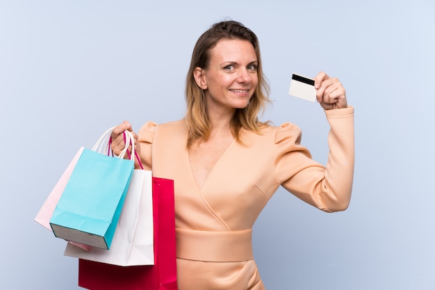 Mujer rubia con bolsas de compras y una tarjeta de crédito