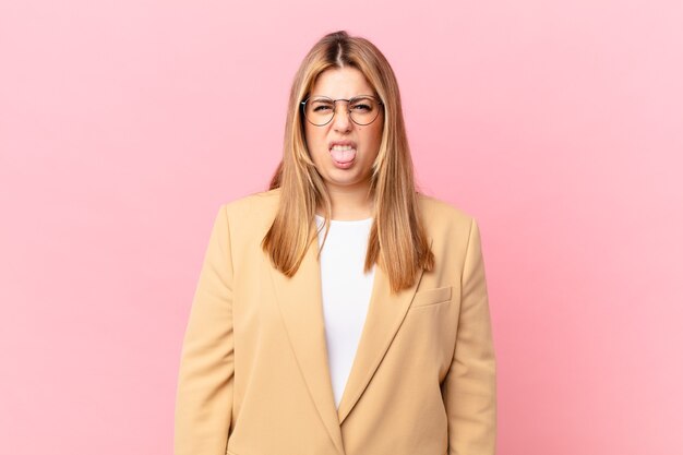 Mujer rubia bonita con curvas que se siente disgustada e irritada y con la lengua fuera