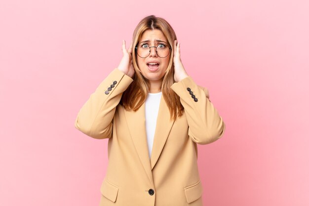 Mujer rubia bonita con curvas que se siente estresada, ansiosa o asustada, con las manos en la cabeza