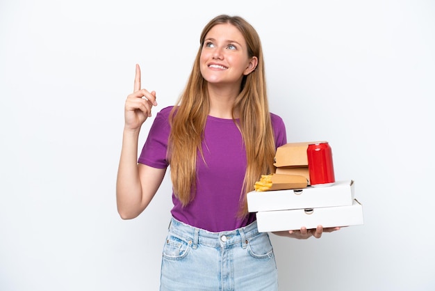 Mujer rubia bonita joven que sostiene la comida rápida aislada en el fondo blanco que señala una gran idea