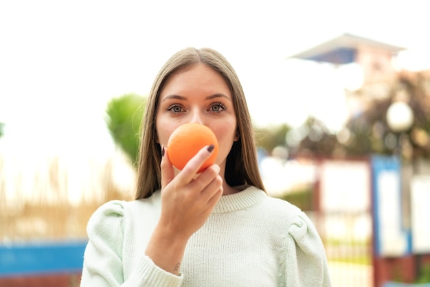 Mujer rubia bonita joven que sostiene una naranja