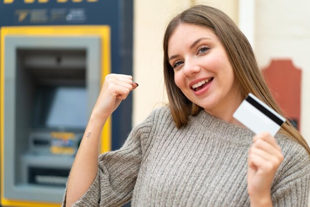 Foto mujer rubia bonita joven que usa un cajero automático