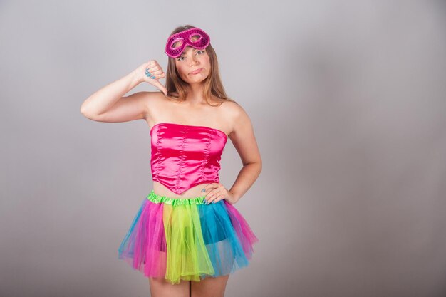 Mujer rubia brasileña vestida con ropa de carnaval rosa enmascara signo de disgusto desaprobación negativa