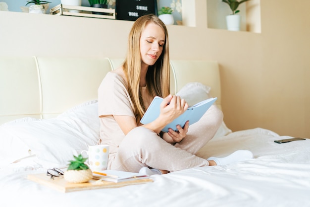 Mujer rubia en la cama con libro