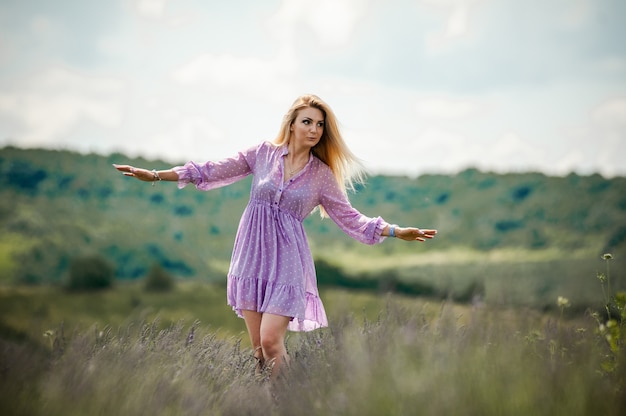 Mujer rubia caminando por el campo de lavanda