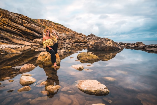 Mujer rubia en una camisa floral en las rocas