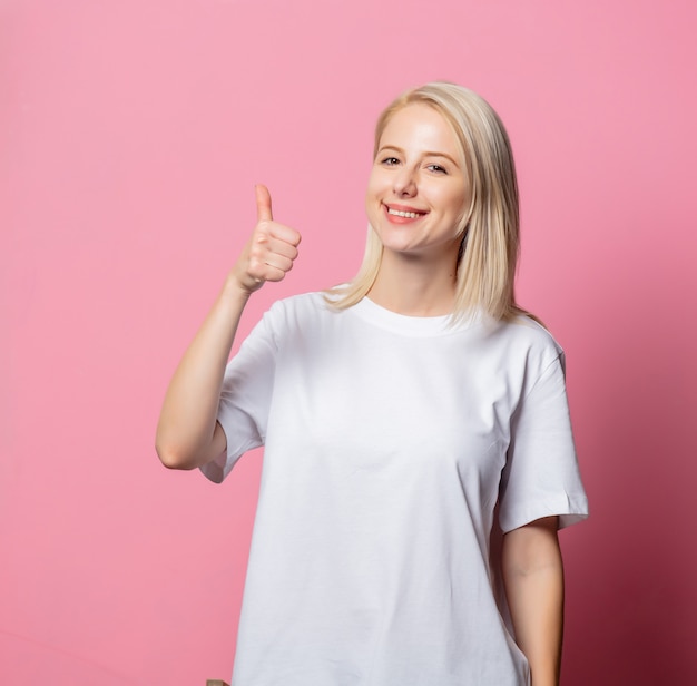 Mujer rubia en camiseta blanca en rosa