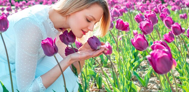 Mujer rubia en un campo de tulipanes sonriendo hermosa mujer morena con tulipanes en un campo de flores