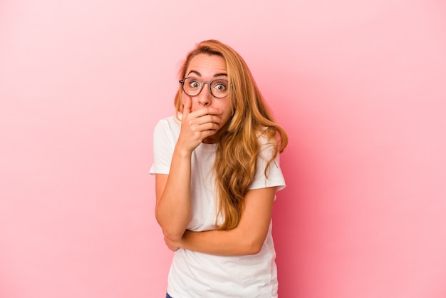 Mujer rubia caucásica aislada sobre fondo rosa asustada y asustada.