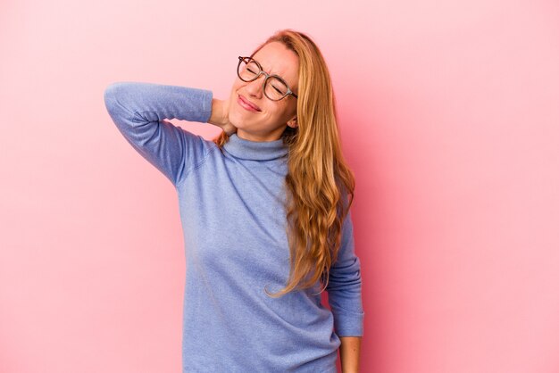 Mujer rubia caucásica aislada sobre fondo rosa masajeando el codo, sufriendo después de un mal movimiento.