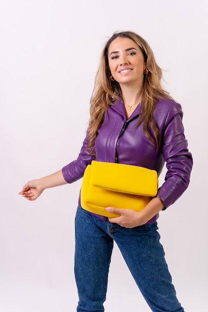 Mujer rubia caucásica sonriendo con una bolsa amarilla en un estudio de moda de medio cuerpo de fondo blanco