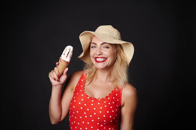 Mujer rubia caucásica en traje de baño rojo con lunares blancos y sombrero de paja de verano con str