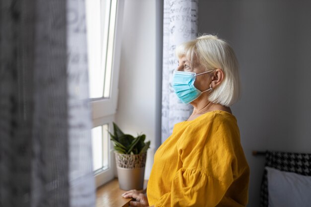 Mujer rubia en cuarentena de máscara en aislamiento en casa por brote de virus. Concepto de estancia en casa