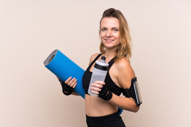 Mujer rubia deporte con botella de agua deportiva y con una estera