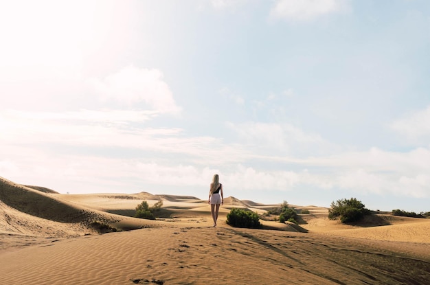 Mujer rubia en el desierto de dunas en un día soleado