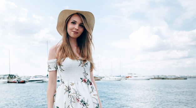 mujer rubia elegante en un muelle en verano