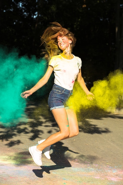 Mujer rubia emocional saltando con colores vibrantes explotando a su alrededor