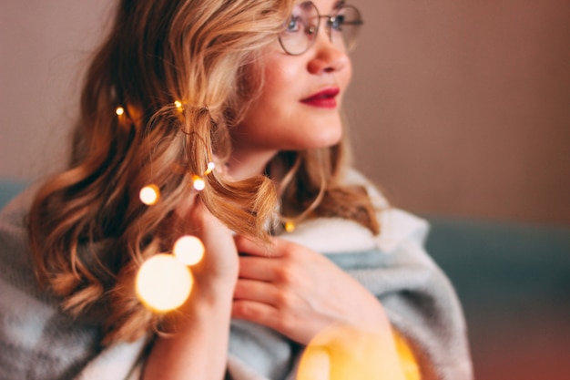 Mujer rubia encantadora joven en vidrios con las luces en su pelo