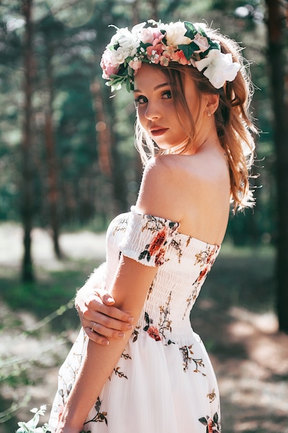 mujer rubia con estilo floral en un bosque verde