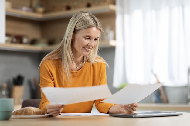 Mujer rubia feliz freelancer trabajando desde casa leyendo periódicos