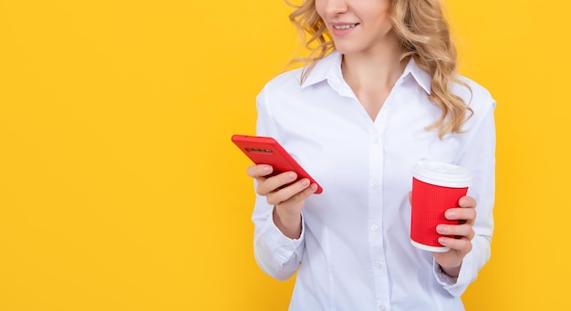 Mujer rubia feliz con taza de café charlando por teléfono sobre fondo amarillo