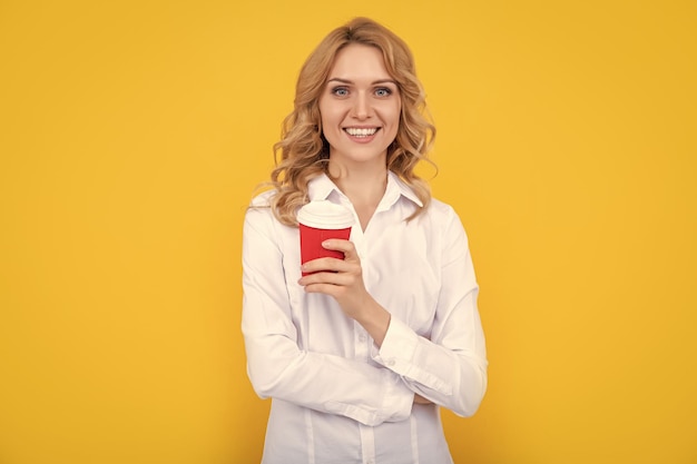 Mujer rubia feliz con taza de café por la mañana sobre fondo amarillo