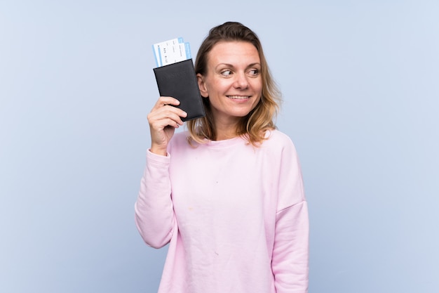 Mujer rubia feliz en vacaciones con pasaporte y boletos de avión