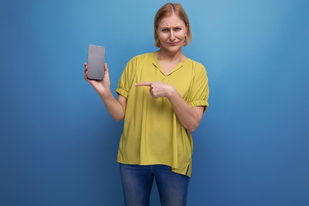 Mujer rubia frustrada de mediana edad sosteniendo un teléfono inteligente en sus manos verticalmente con una maqueta