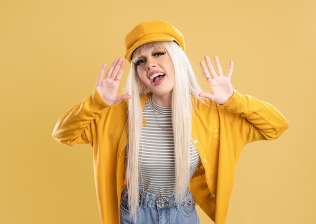 Mujer rubia con gorra y chaqueta amarilla Con las manos en la boca dibujando