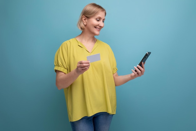 La mujer rubia hace una compra en línea pagando con su tarjeta de dinero