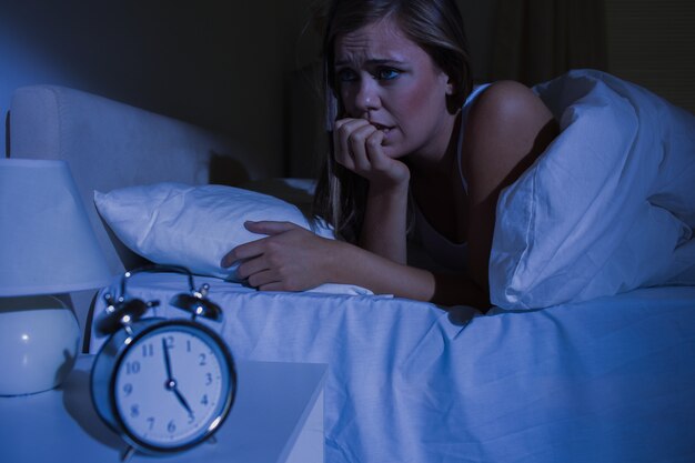 Foto mujer rubia inquieta en la cama por la noche