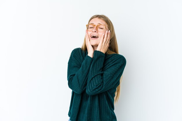 Mujer rubia joven aislada en blanco lloriqueando y llorando desconsoladamente.