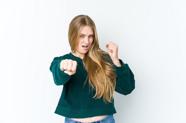 Mujer rubia joven aislada en el espacio en blanco lanzando un puñetazo, ira, luchando debido a una discusión, boxeo.