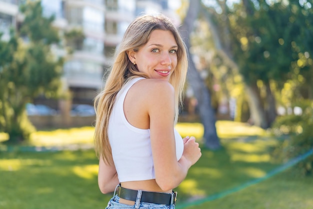 Mujer rubia joven al aire libre con expresión feliz