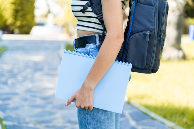 Mujer rubia joven al aire libre sosteniendo un cuaderno