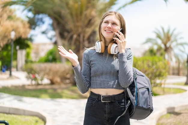 Mujer rubia joven al aire libre usando teléfono móvil