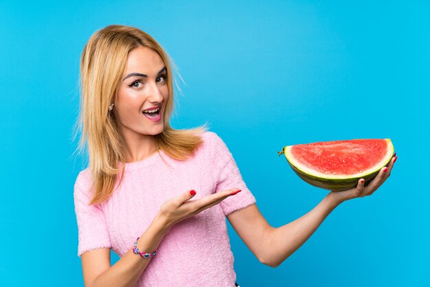 Mujer rubia joven feliz que sostiene las frutas