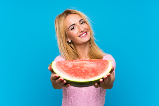 Mujer rubia joven feliz que sostiene las frutas