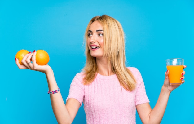 Mujer rubia joven feliz que sostiene las frutas