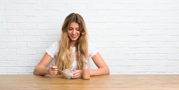 Mujer rubia joven feliz con tazón de cereales