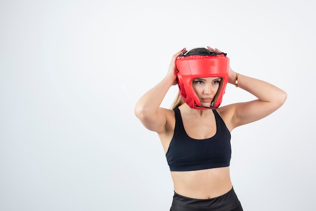 Mujer rubia joven en la presentación del casco de boxeo rojo.