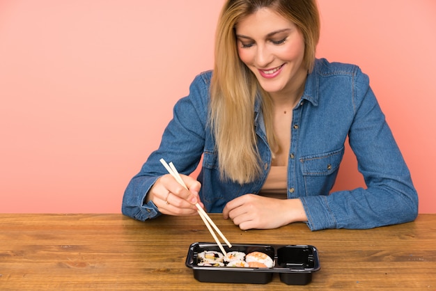 Foto mujer rubia joven que come el sushi
